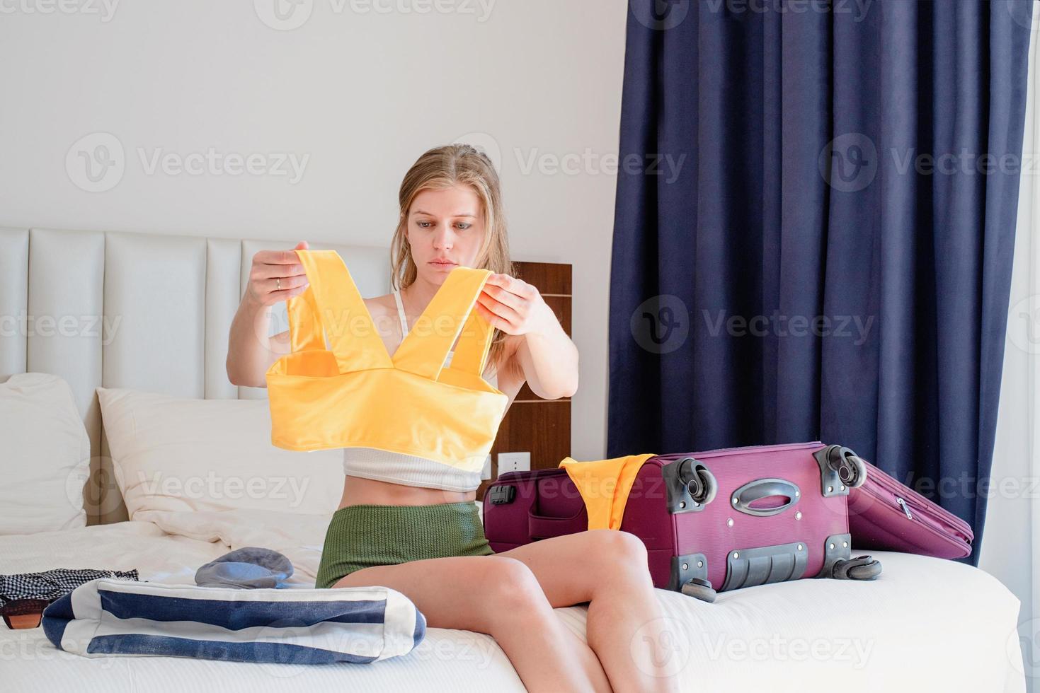 Excited young caucasian woman packing bags for holidays photo