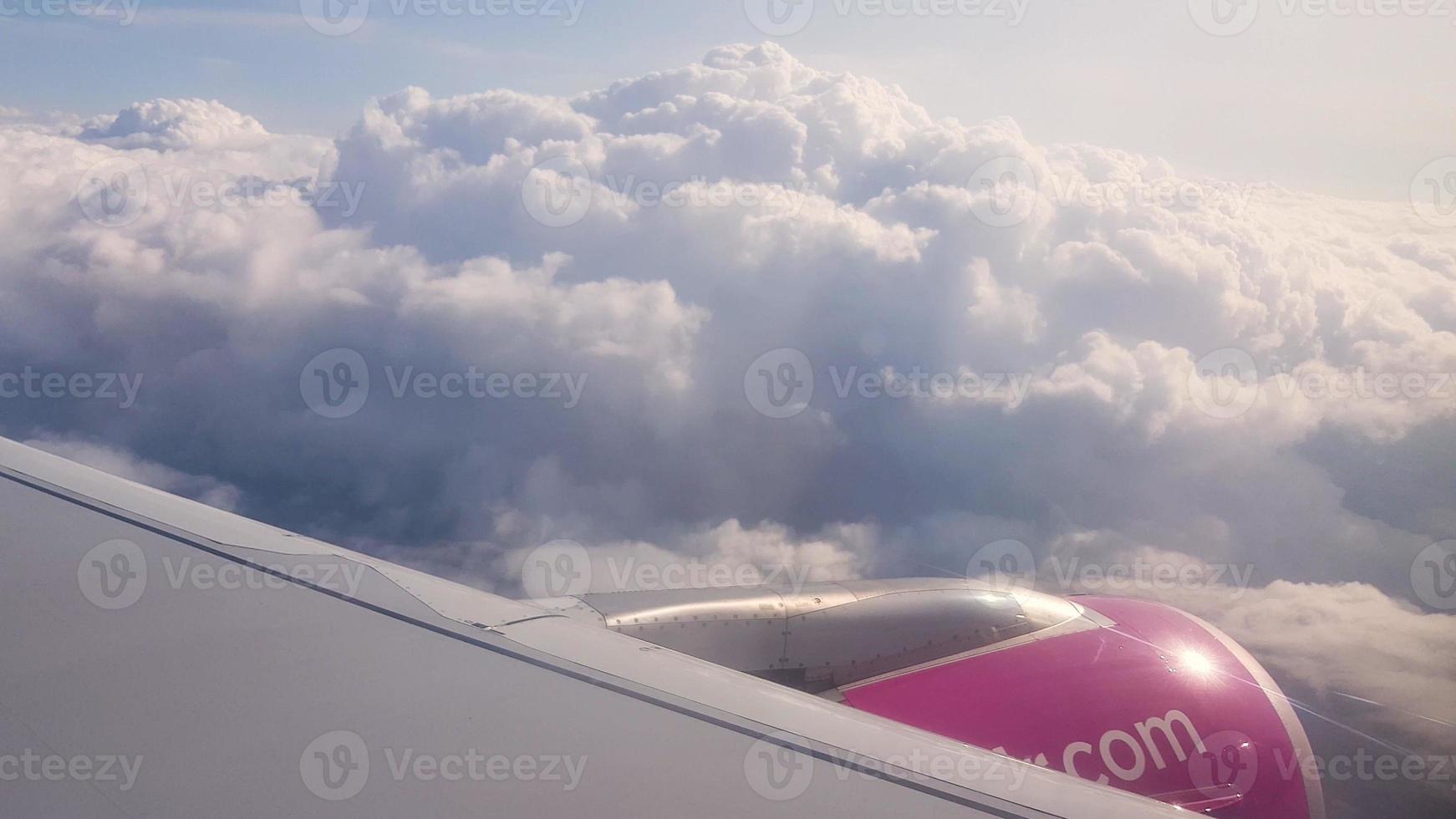 Flying over the clouds. View from plane aircraft passenger window with clouds and skyline horizon. photo
