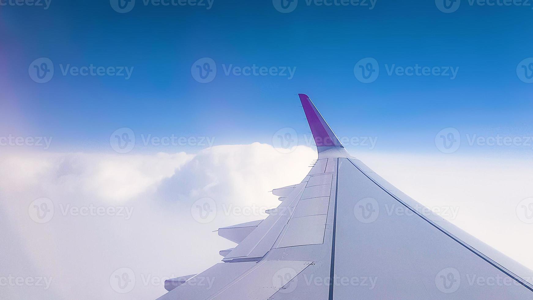 Flying over the clouds. View from plane aircraft passenger window with clouds and skyline horizon. photo