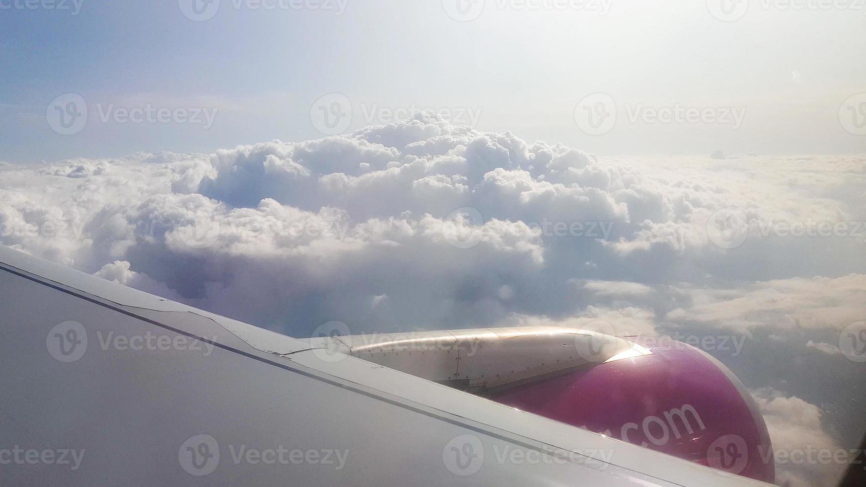 Flying over the clouds. View from plane aircraft passenger window with clouds and skyline horizon. photo