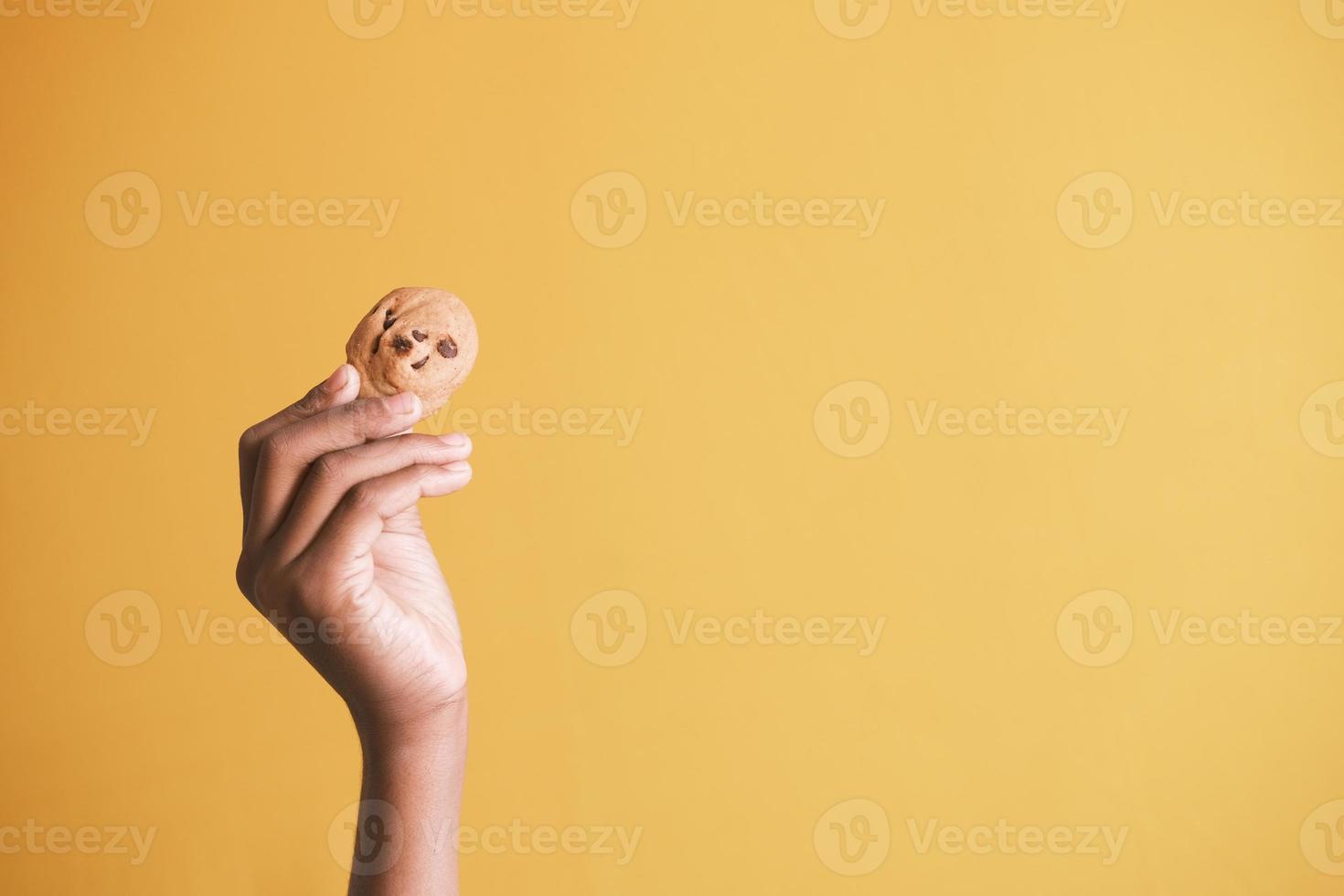 holding a sweet cooking against yellow background photo