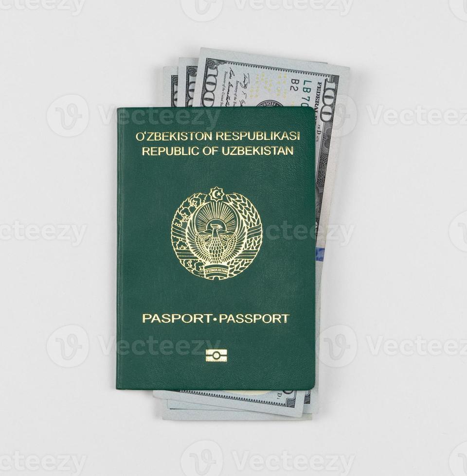 pasaporte de uzbekistán con dólares americanos sobre fondo blanco, aislado. vista superior foto