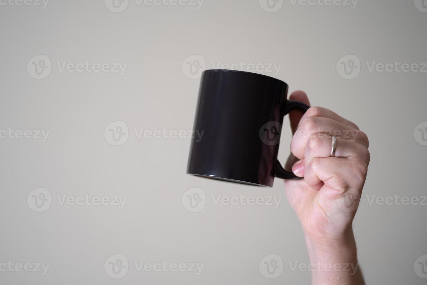 Black mug in the hands of a man on a light background. photo