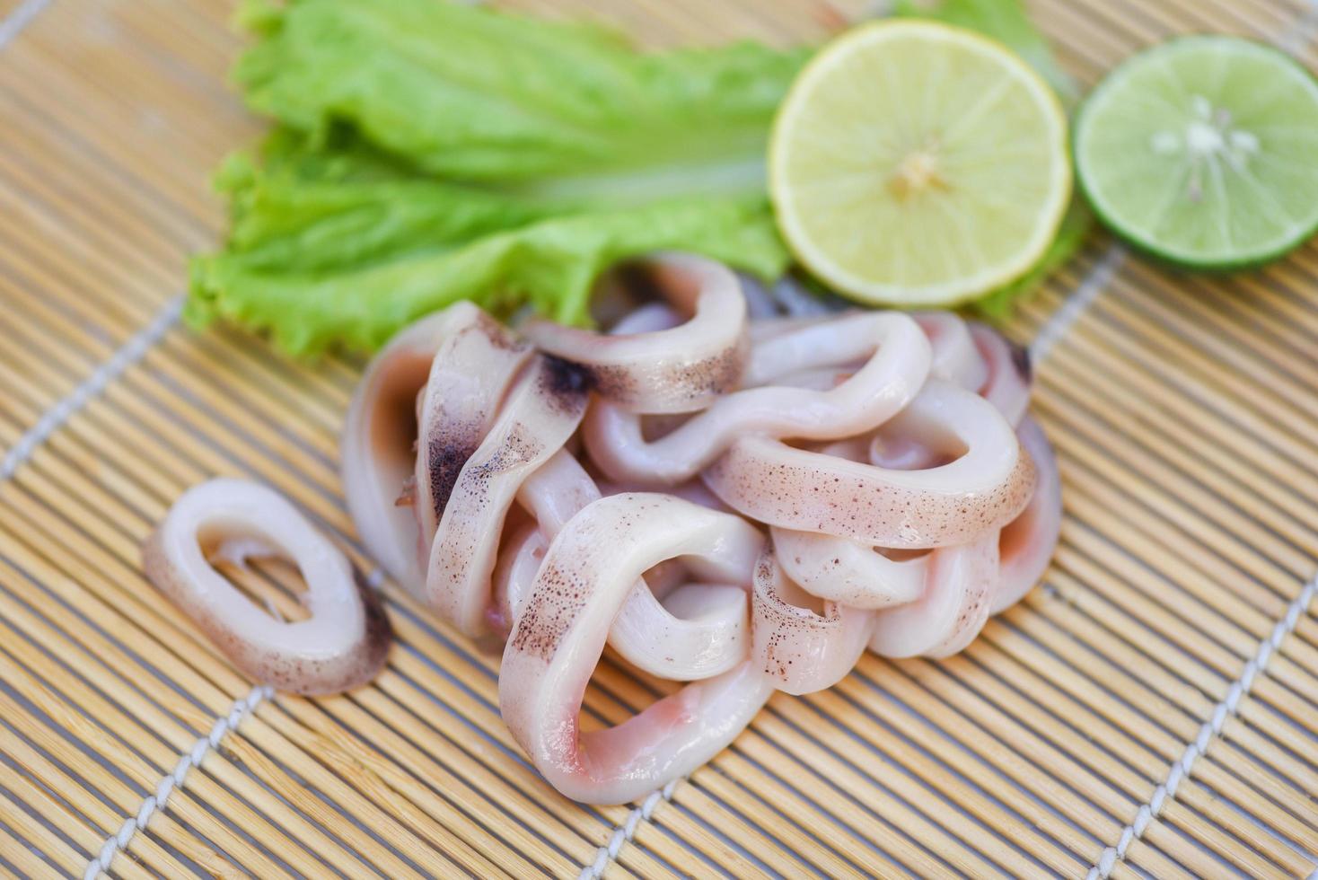 Squid rings on wooden plate, Fresh raw squid for cooked with lettuce vegetable salad and lemon lime photo