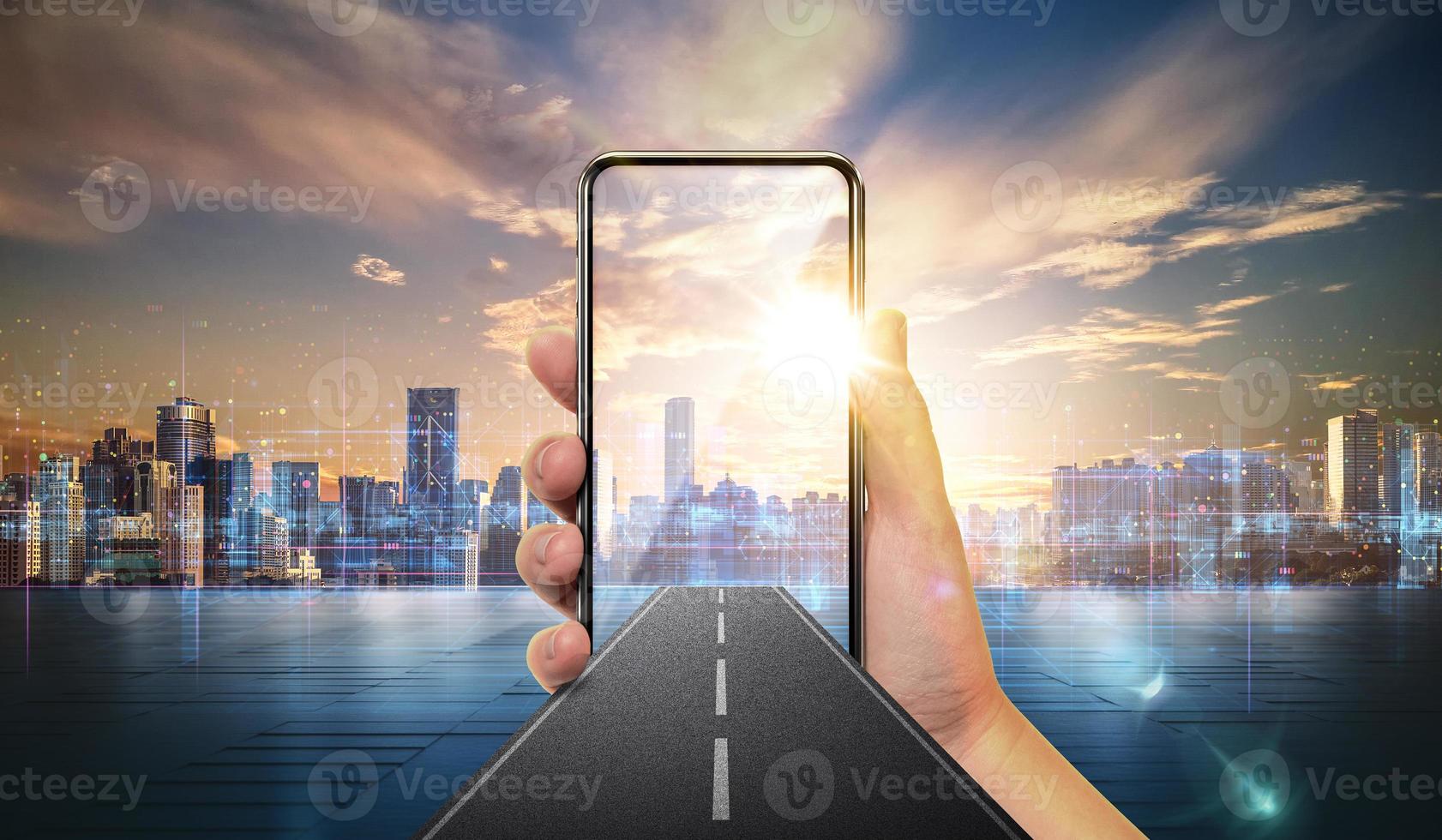 creative design with mobile phone in hand, road coming out of smartphone with city skyline background. photo