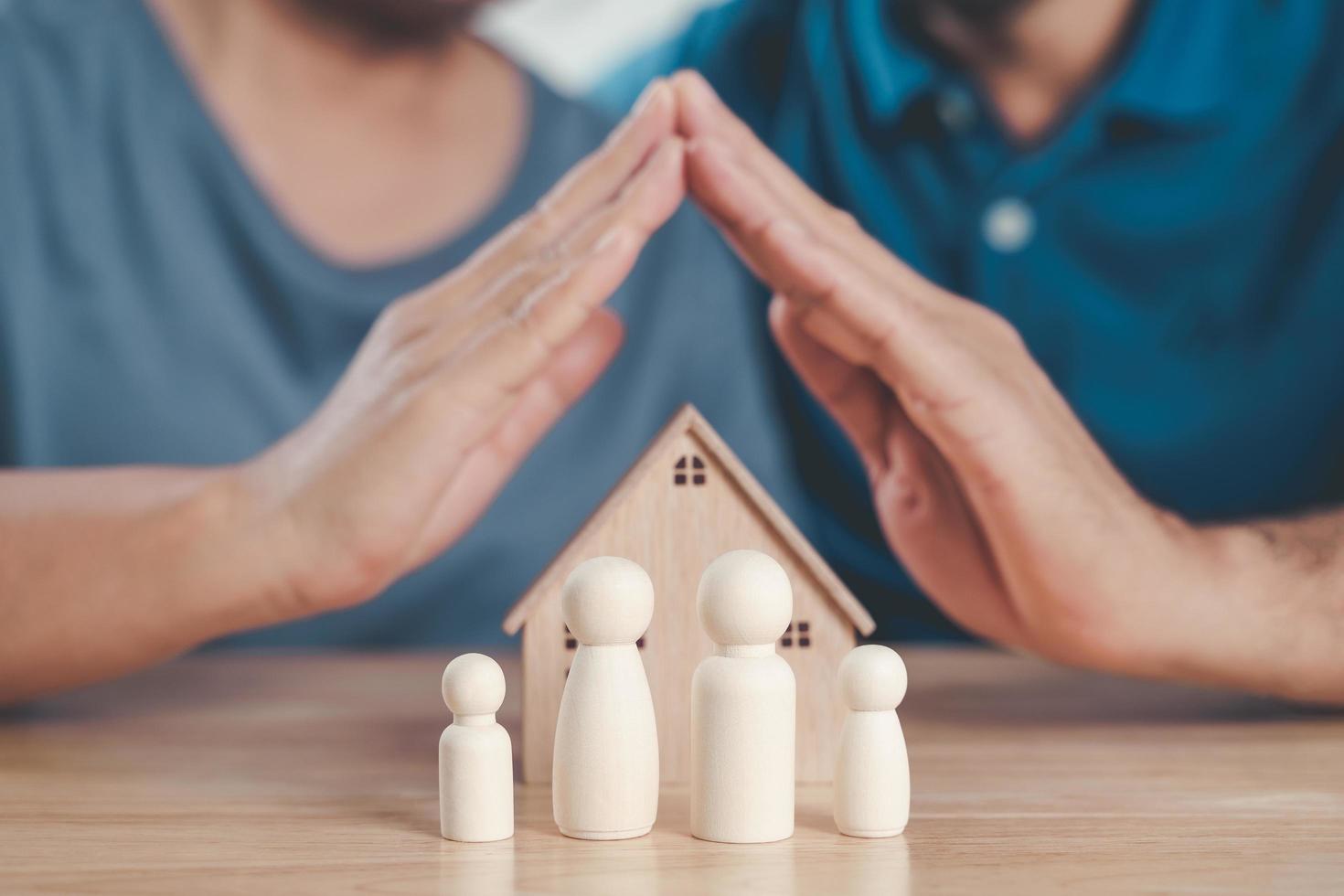 Man and Woman Hands protect over wooden peg dolls. planning, saving family,  health care and insurance, family mental health, international day of families photo