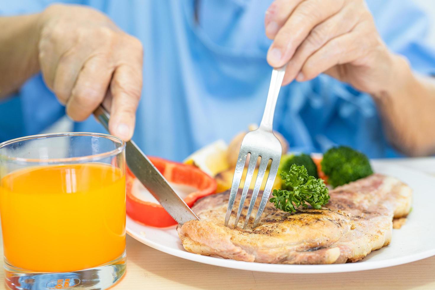 Asian senior or elderly old lady woman patient eating breakfast and vegetable healthy food with hope and happy while sitting and hungry on bed in hospital. photo