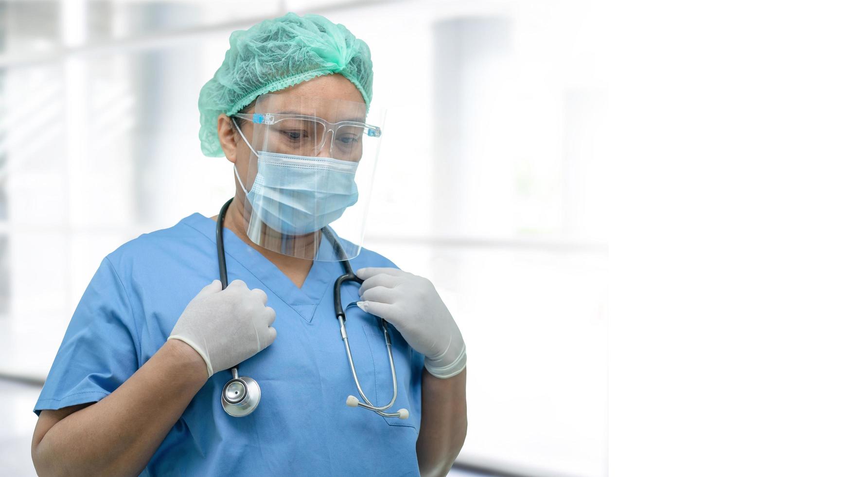 Asian doctor wearing face shield and PPE suit new normal to check patient protect safety infection Covid-19 Coronavirus outbreak at quarantine nursing hospital ward. photo