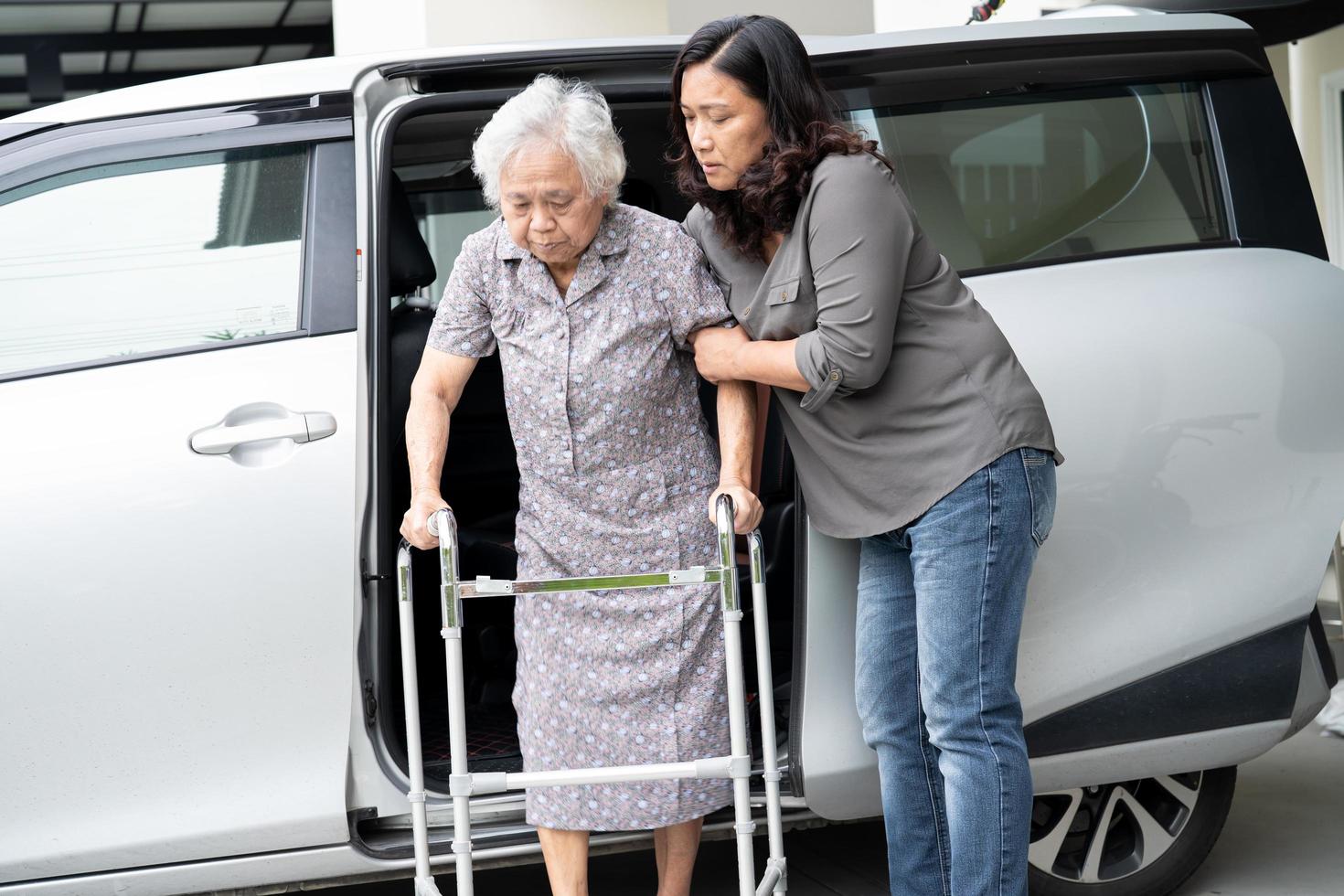 Caregiver daughter help and support asian senior or elderly old lady woman patient prepare get out her car. photo