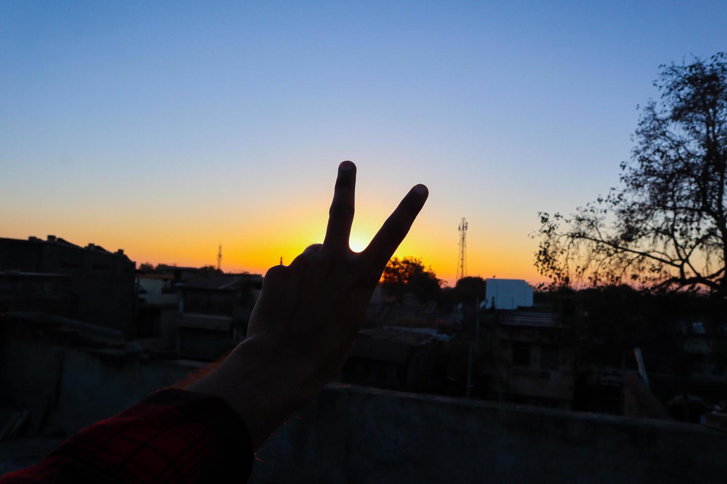 vista del atardecer o del amanecer detrás del signo de la mano. foto