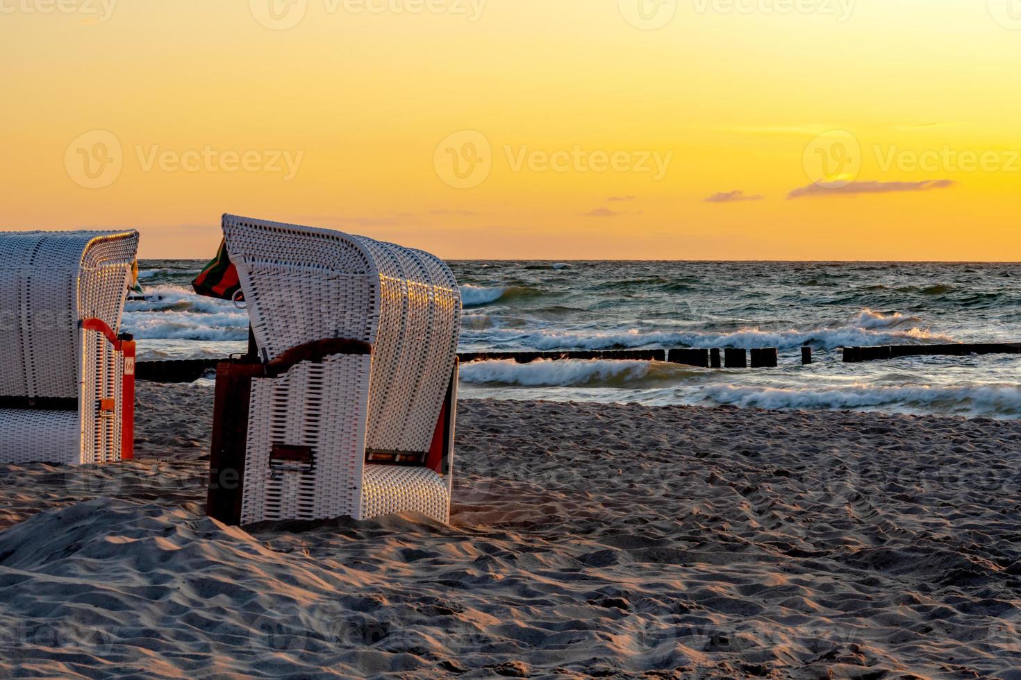 Beach chairs stand in the sunset on a beach on the Baltic Sea with sea photo