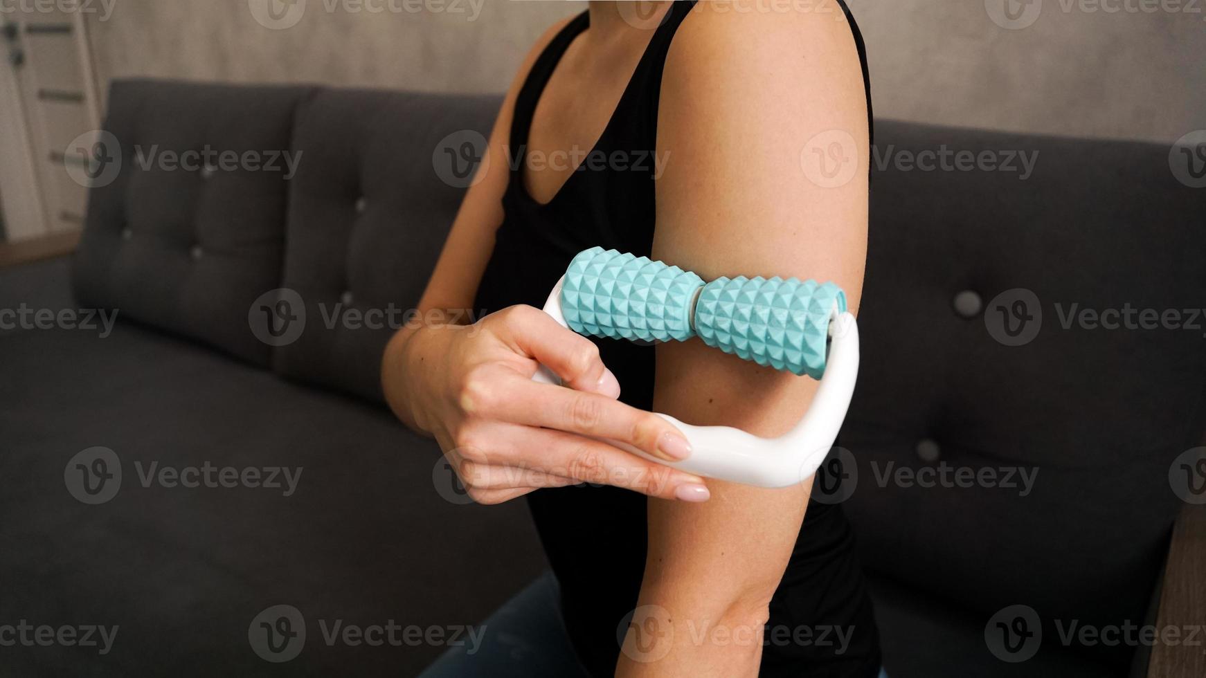 Woman massaging herself with body roller at home photo