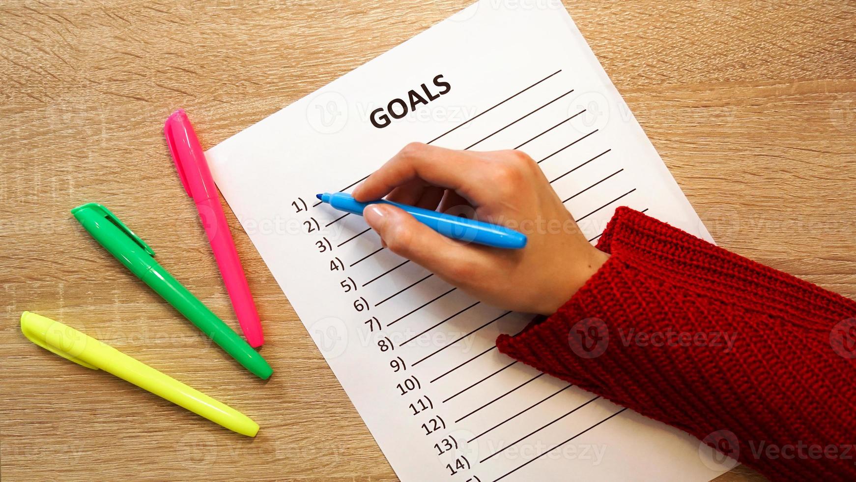 Woman writing down her goals list by colored markers photo