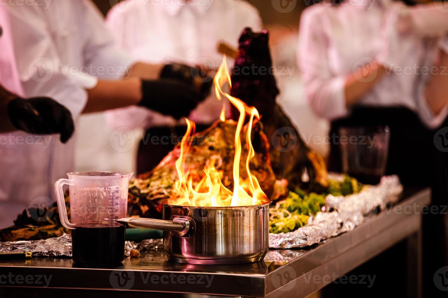 show de cocina, el cocinero prepara la comida en una sartén con fuego. el chef prepara comida con espectáculo de fuego en el restaurante. enfoque selectivo foto