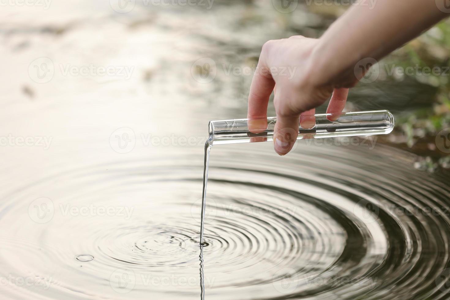 Close up shot of scientist biologist and researcher in protective suit taking water samples from polluted river. photo