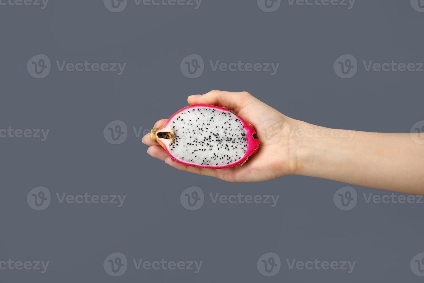 Dragon fruit Top view photo The woman is holding in her hand half fresh pitaya against the grey backdrop. Healthy Lifestyle