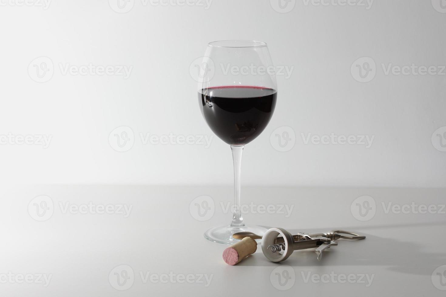 a glass of wine and some wine tools on a white wooden surface. Red wine photo