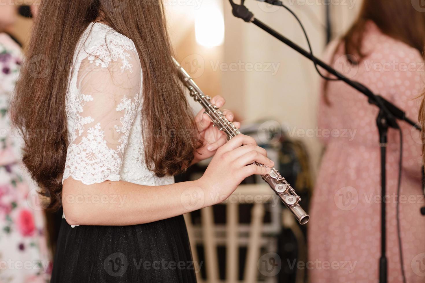 Flutist, young girl playing the flute, hands, fingers on keys closeup, children playing transverse side blow flute, detail shot, classical music, wind instrument performance player up close abstract photo