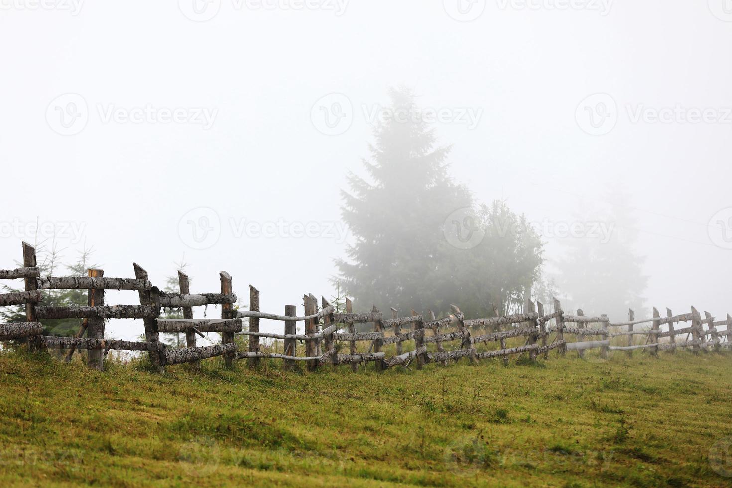 autumn meadow with a old wooden fence on a farm close up, in the Smoky Mountains on a foggy day. travel destination scenic, carpathian mountains photo