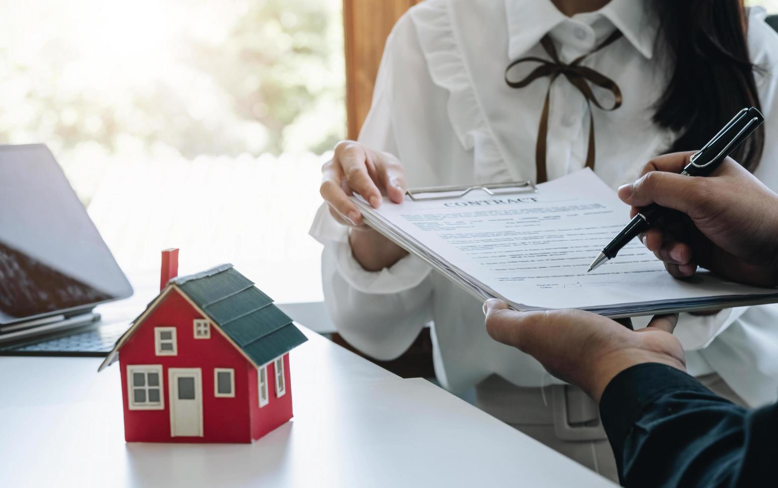 The real estate agent is explaining the house style to the clients who come to contact to see the house design and the purchase agreement. Within a modern office photo