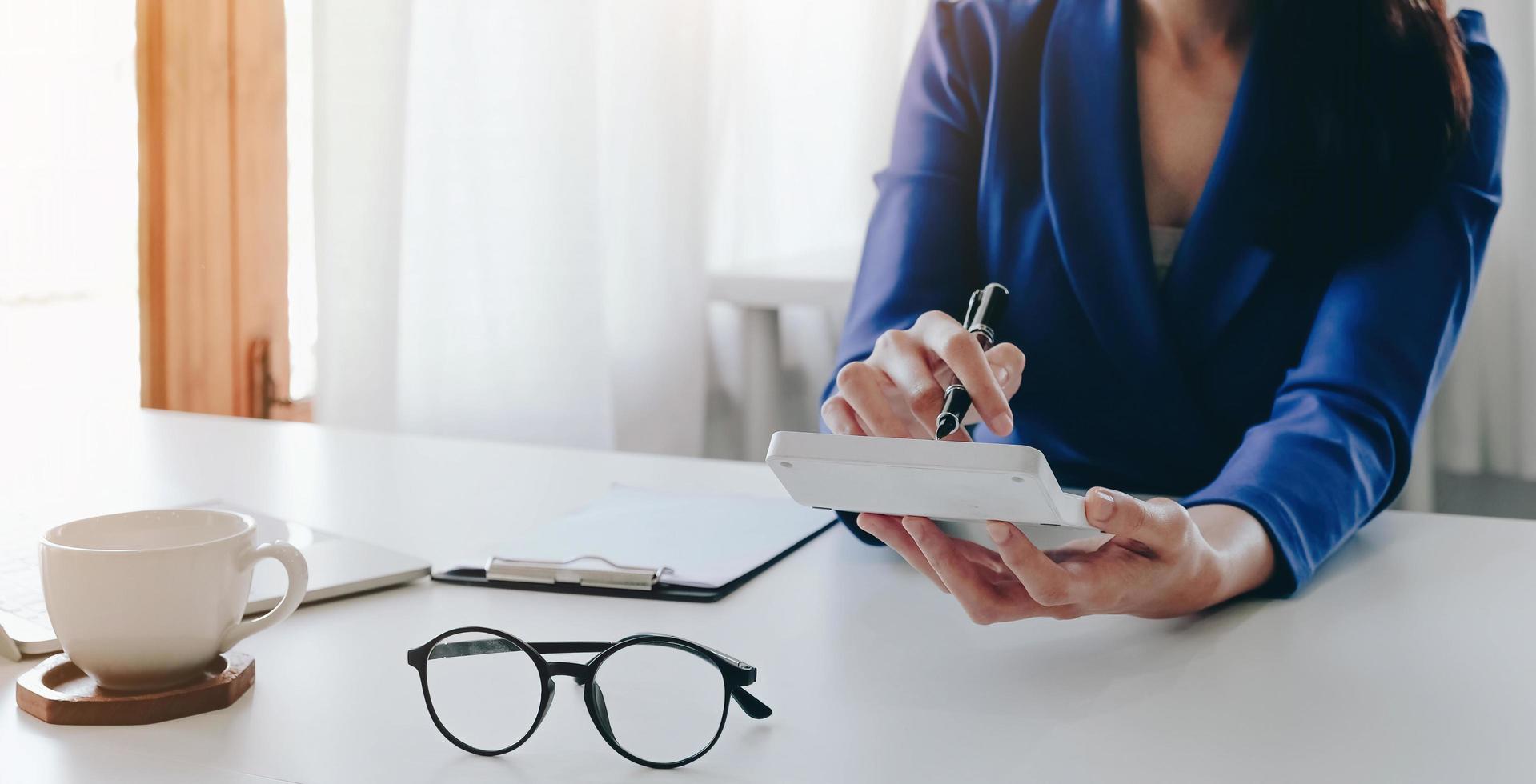 Close up Businesswoman using calculator and laptop for calaulating finance, tax, accounting, statistics and analytic research concept photo