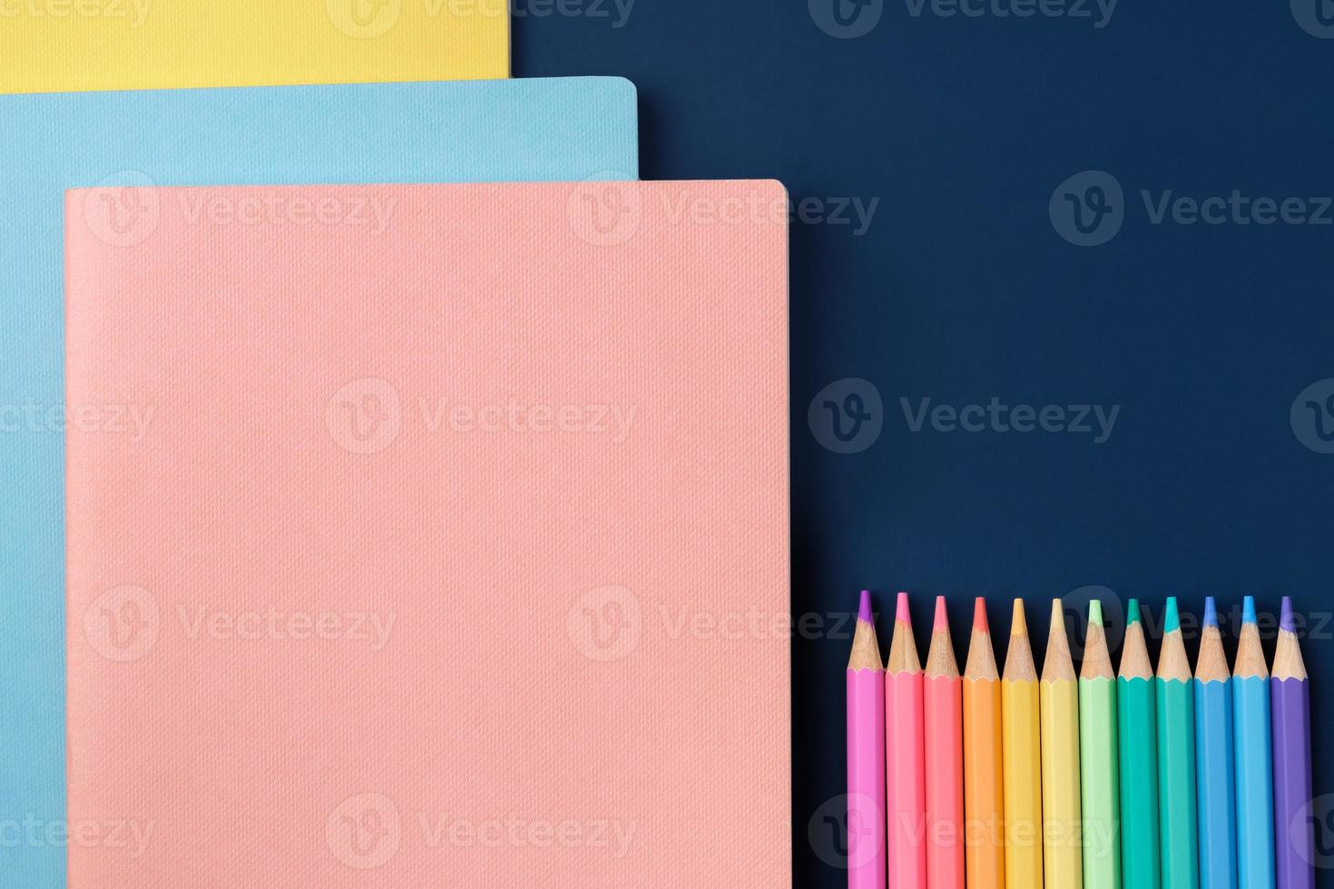 top view pastel notebook with pencil and stationery on navy blue table background photo