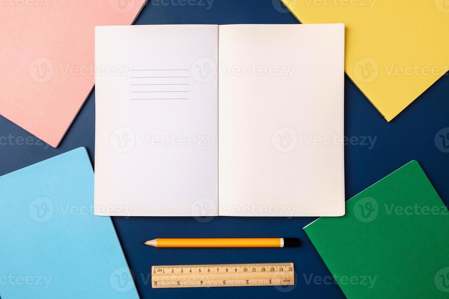 top view pastel notebook with pencil and stationery on navy blue table background photo