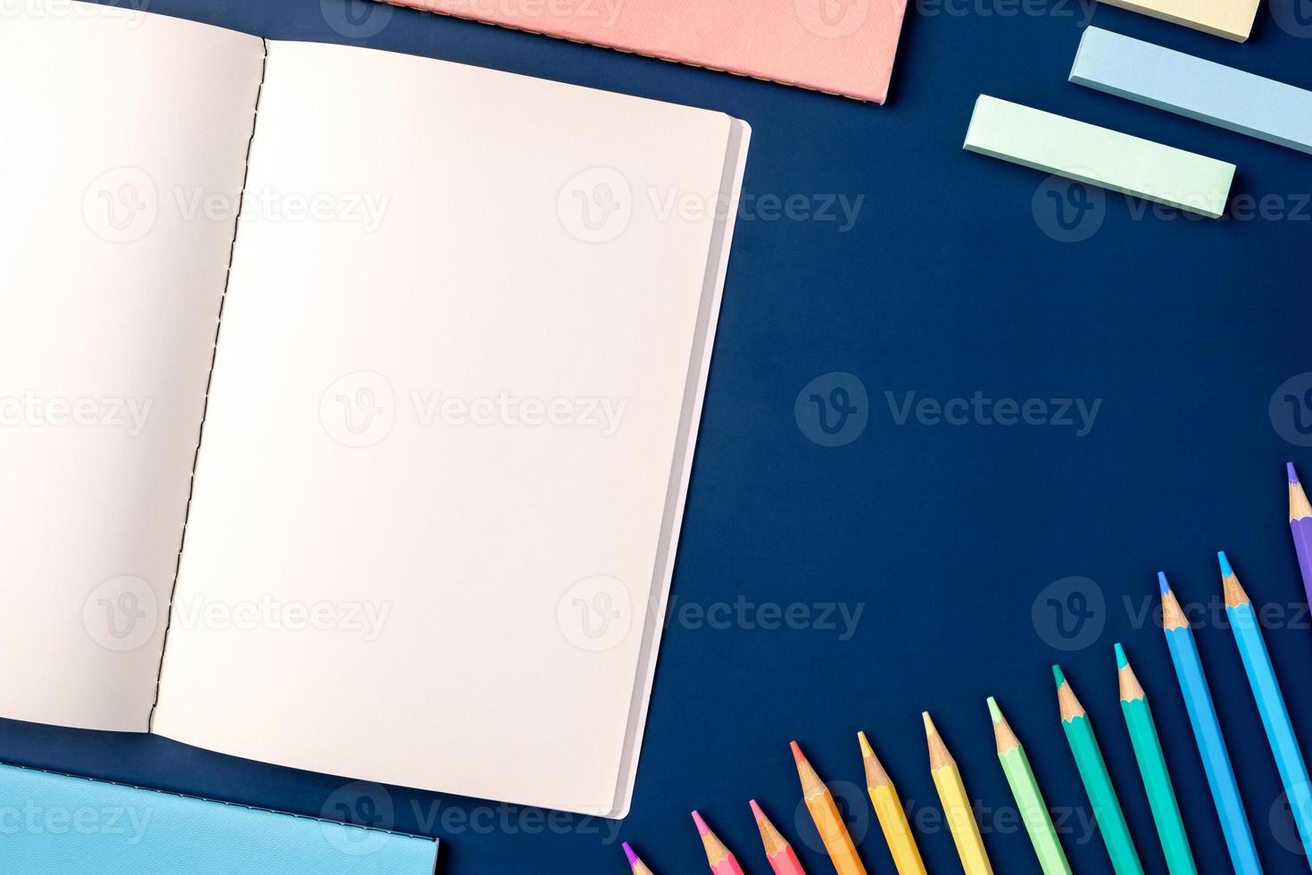 top view pastel notebook with pencil and stationery on navy blue table background photo