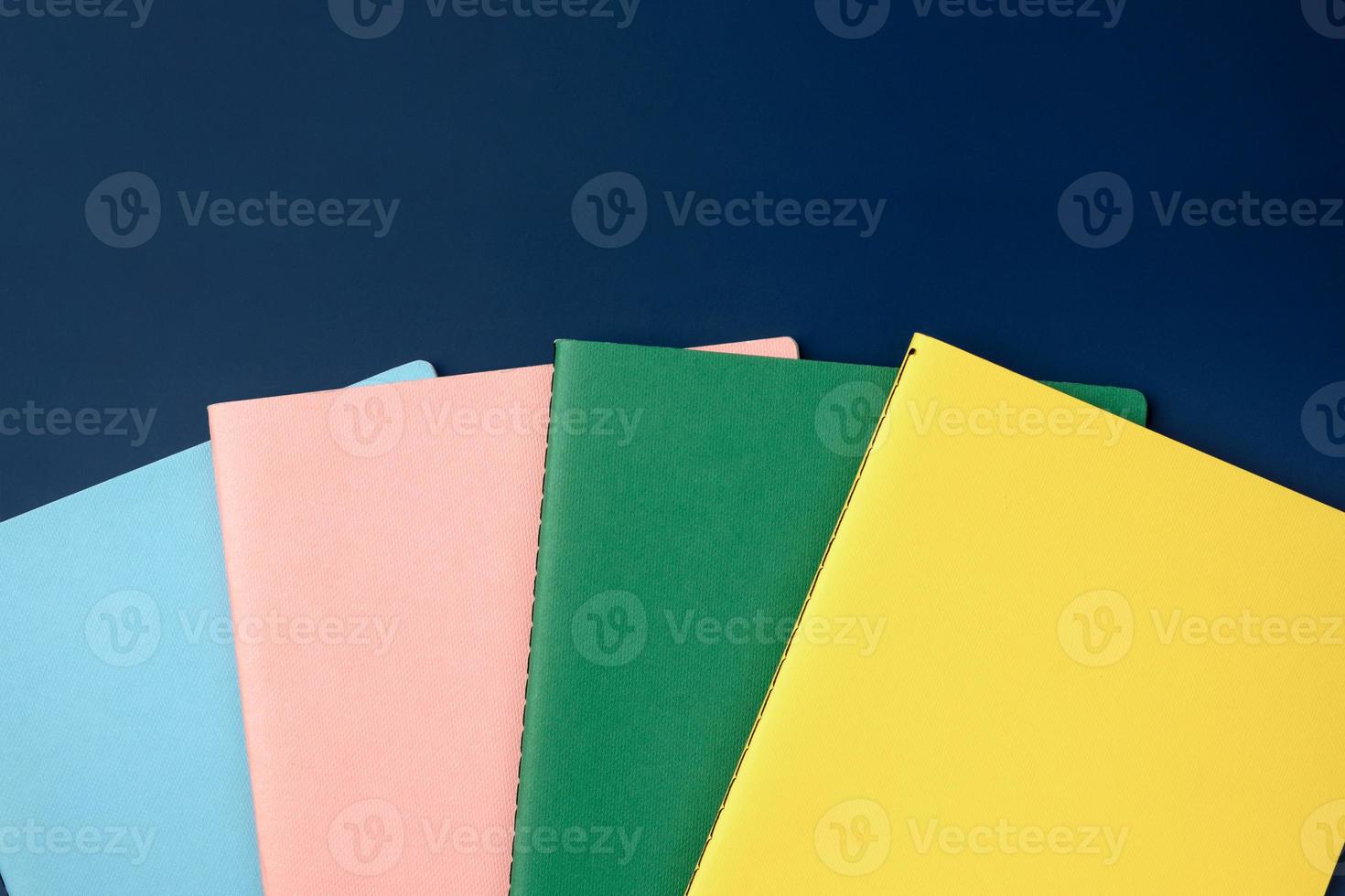 top view pastel notebook with pencil and stationery on navy blue table background photo