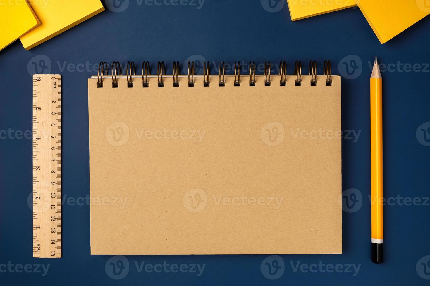 top view brown notebook with yellow pencil and notepad on navy blue working table photo