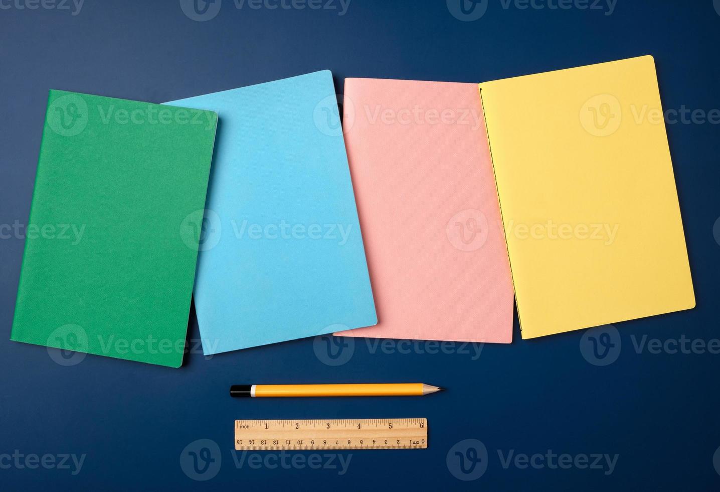 top view pastel notebook with pencil and stationery on navy blue table background photo