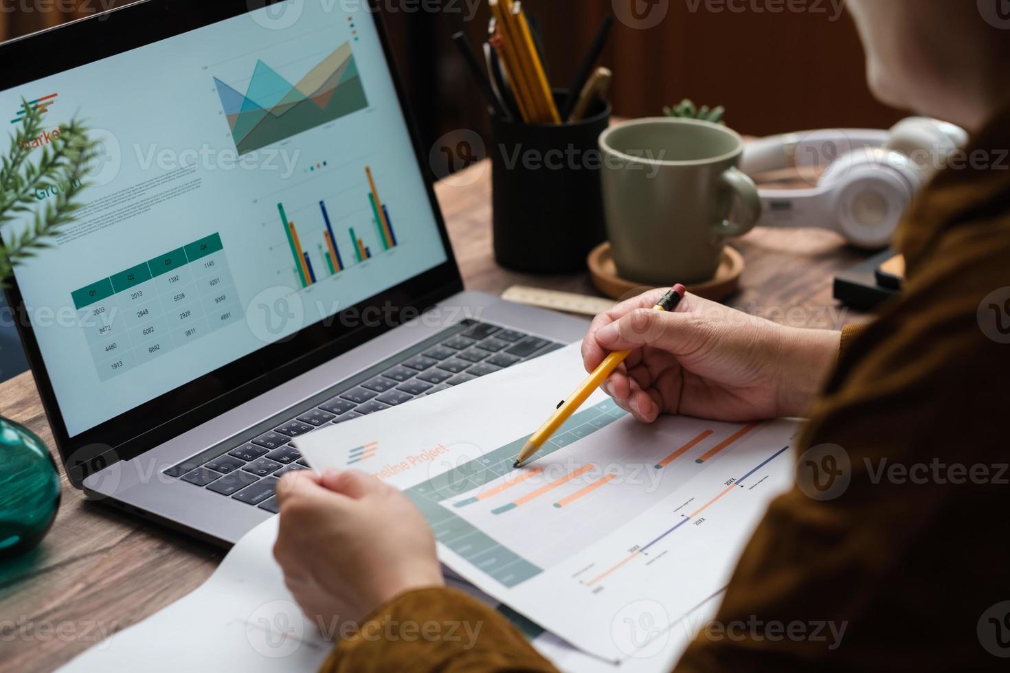 asian woman holding paperwork flow of project checking with laptop data working at home photo