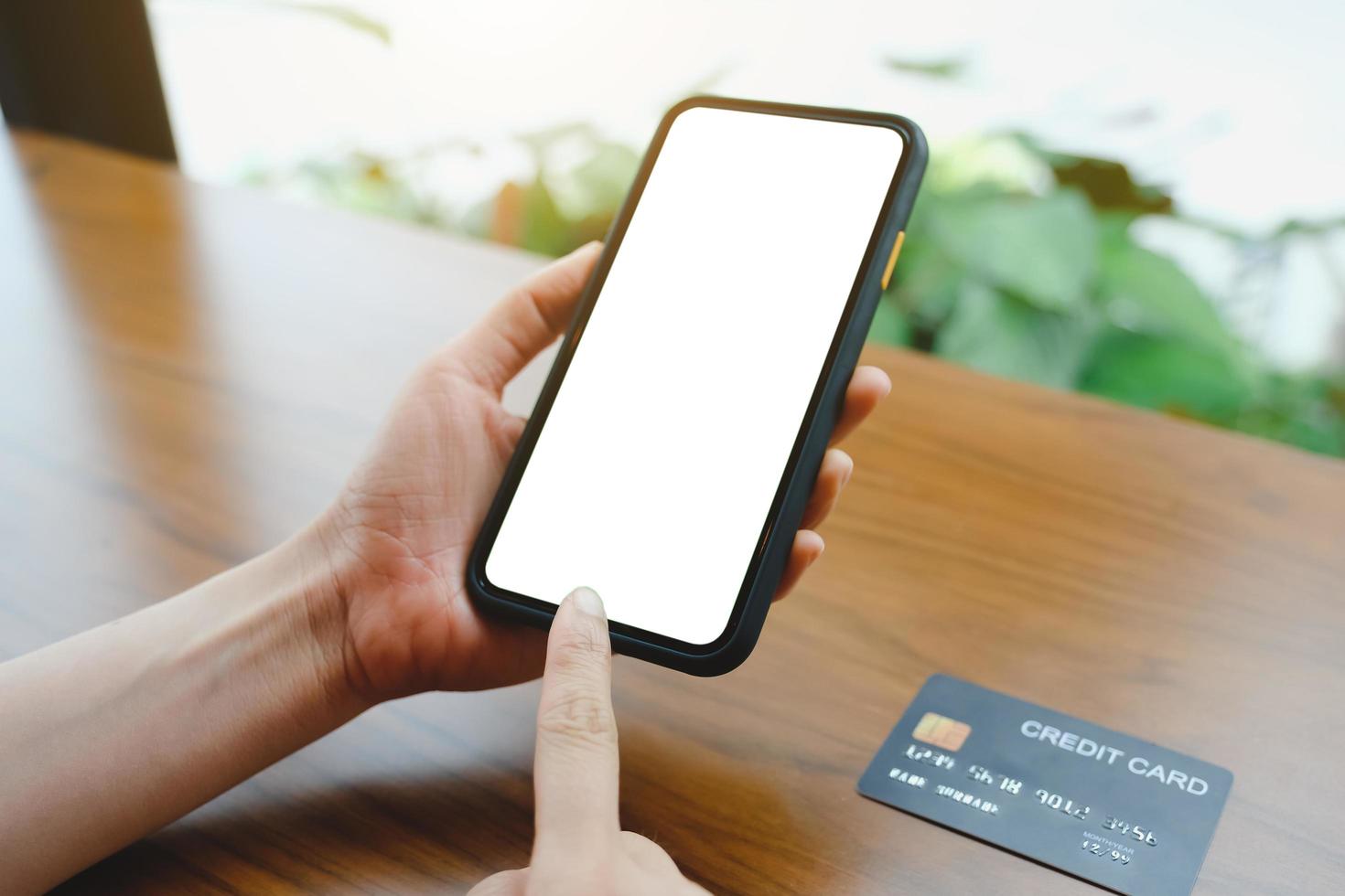 Mockup image of woman's hands holding white mobile phone with blank screen on thigh and coffee cup in cafe. photo