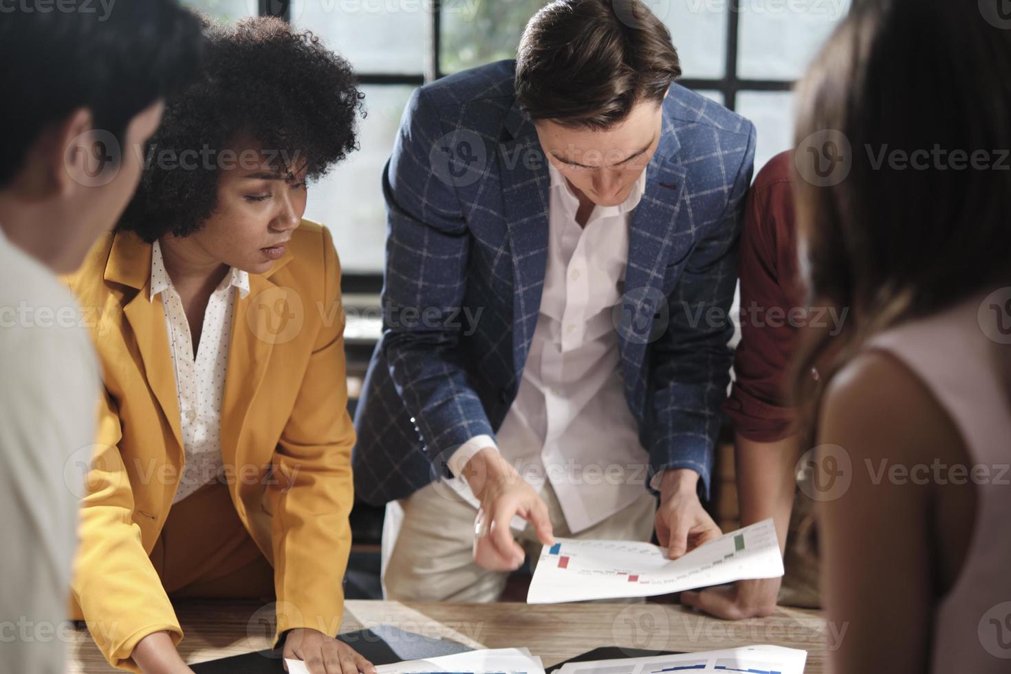 Multiracial coworkers' team and colleagues brainstormed, discussing marketing strategy, ideas collaboration, and business project planning at an office's conference table in staff meeting workplace. photo