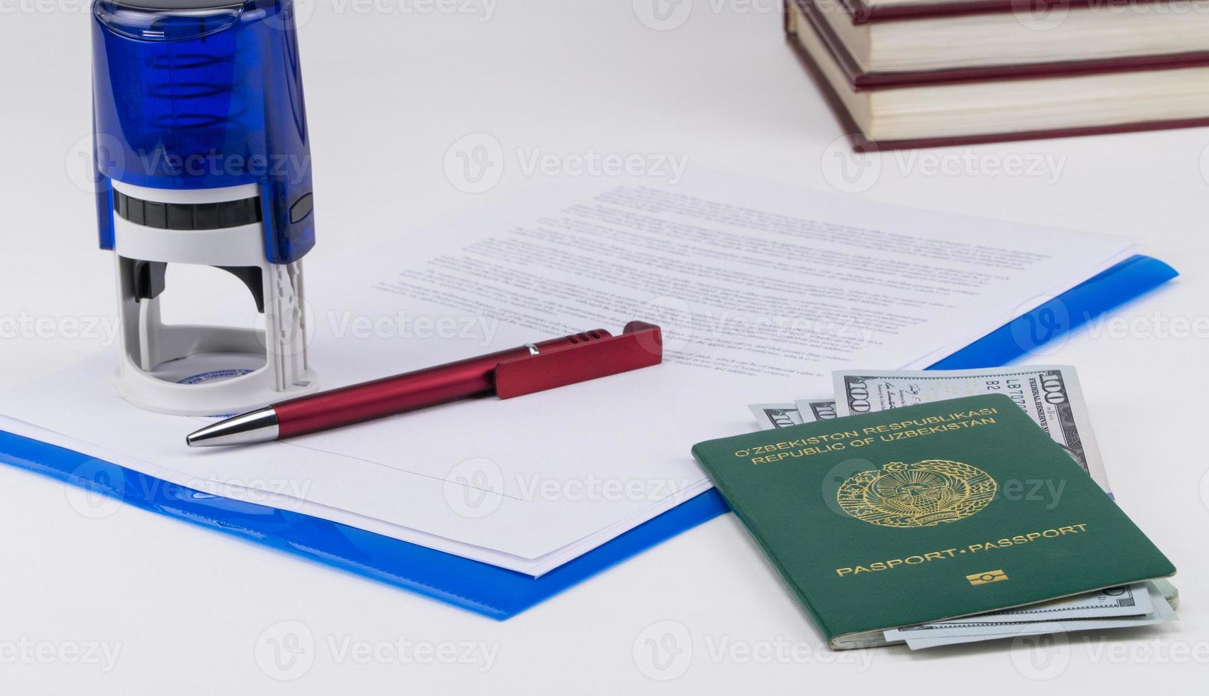 Uzbekistan passport with US dollars on the background of documents and contract. Concept - briber and corruption photo