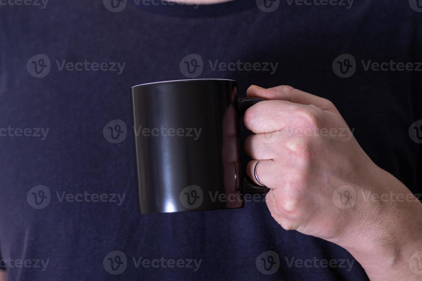 A black mug in the hands of a man. photo