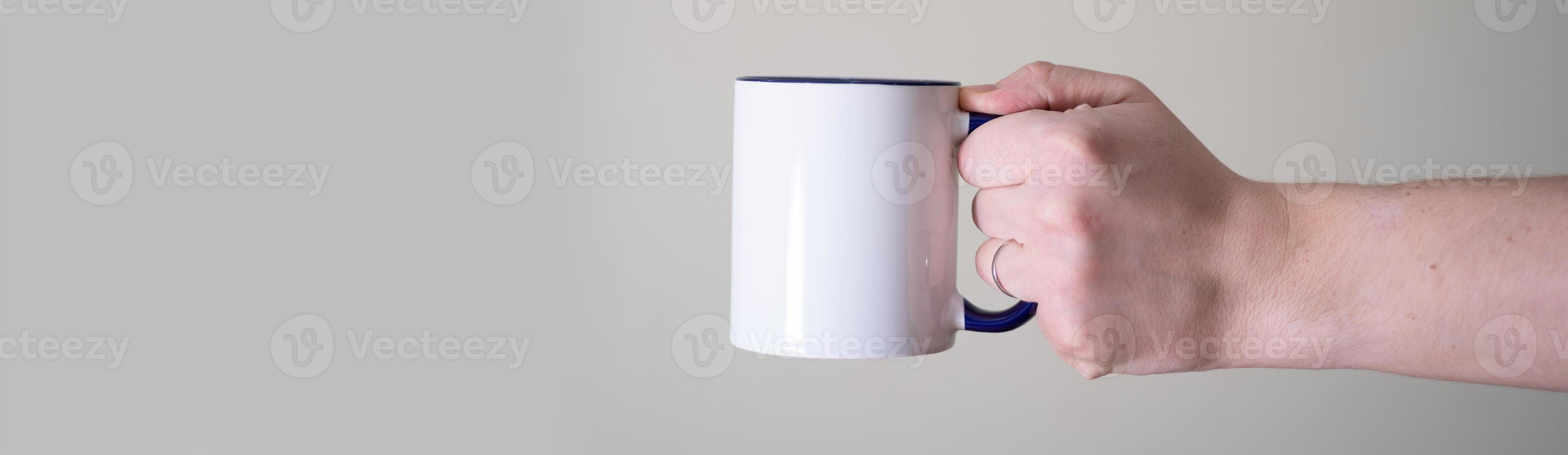 White mug in the hands of a man on a light background. photo