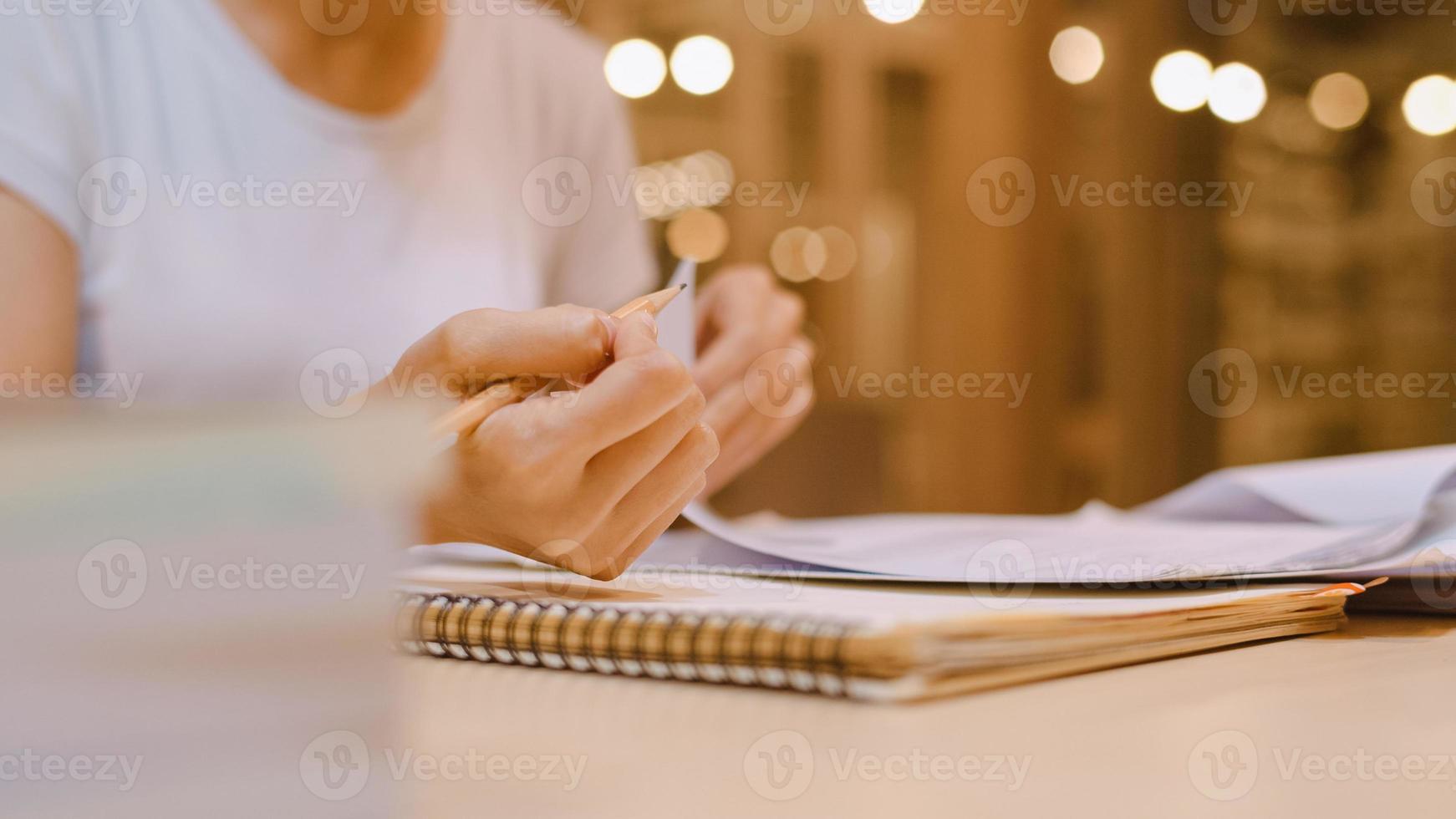Asian student women reading books in library at university. Young undergraduate girl do homework, read textbook, study hard for knowledge on lecture desk at college campus overtime night. photo