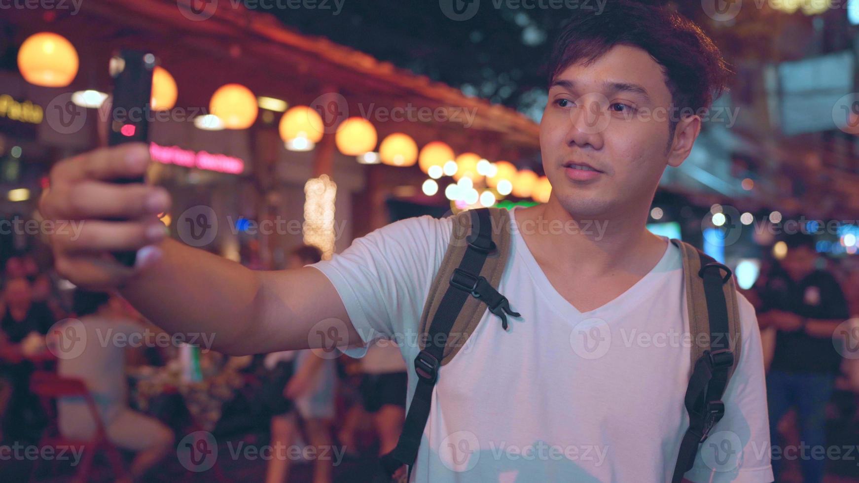 Traveler Asian blogger man travel in Bangkok, Thailand, male using mobile phone make vlog and live in social media while hangout at The Khao San Road. Men travel in Thailand concept. photo