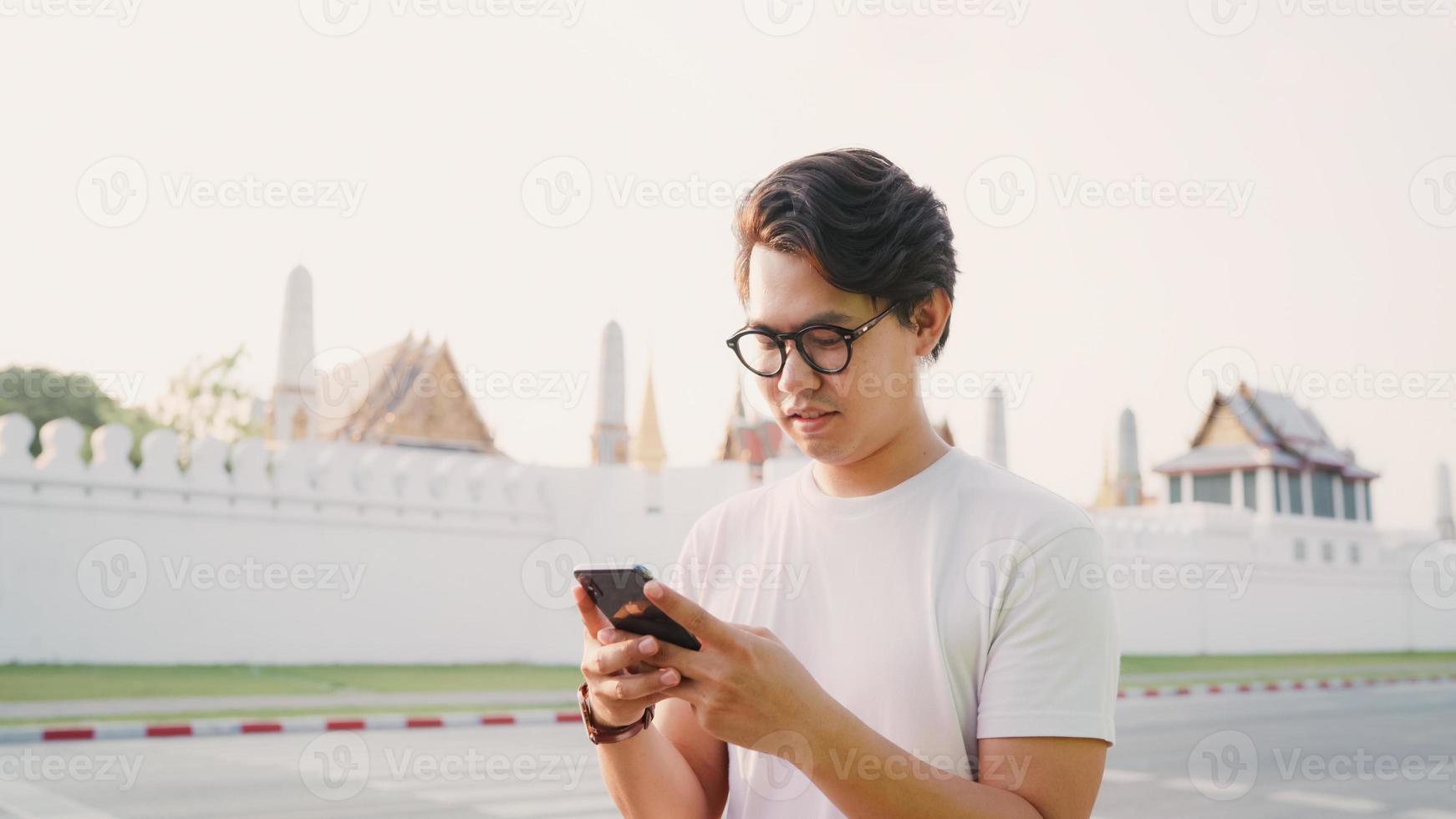 Traveler Asian man direction on location map in Bangkok, Thailand, backpacker male using mobile phone looking on map while spending holiday trip in sunset. Lifestyle men travel in Asia city concept. photo