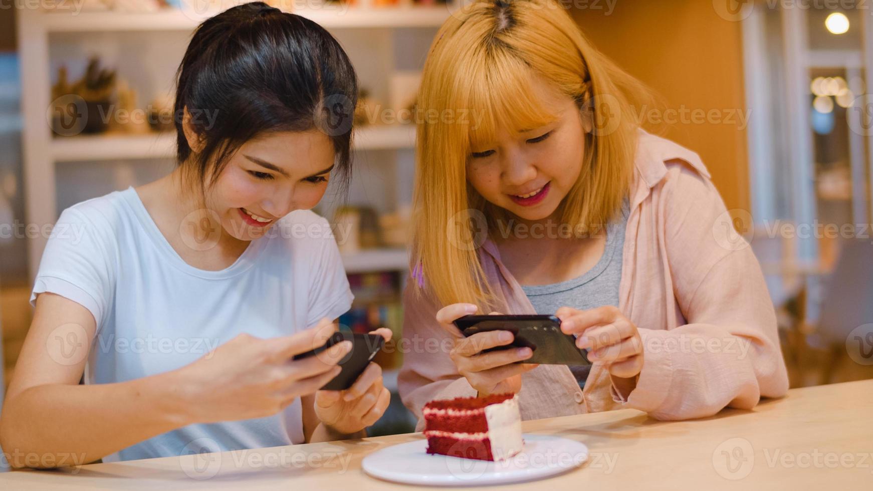 alegre joven amigo de asia usando el teléfono tomando una fotografía de comida y pastel en la cafetería. dos alegres y atractivas damas asiáticas juntas en un restaurante o cafetería. actividad de vacaciones o concepto de estilo de vida moderno. foto