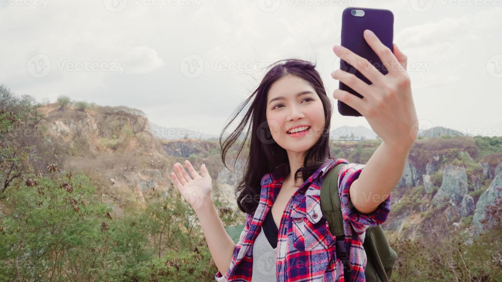 Asian backpacker woman selfie on top of mountain, young female happy using mobile phone taking selfie enjoy holidays on hiking adventure. Lifestyle women travel and relax concept. photo