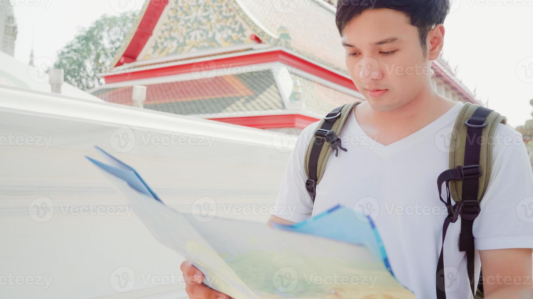 Traveler Asian man direction on location map in Bangkok, Thailand, backpacker male looking on map find landmark while spending holiday trip. Lifestyle men travel in Asia city concept. photo