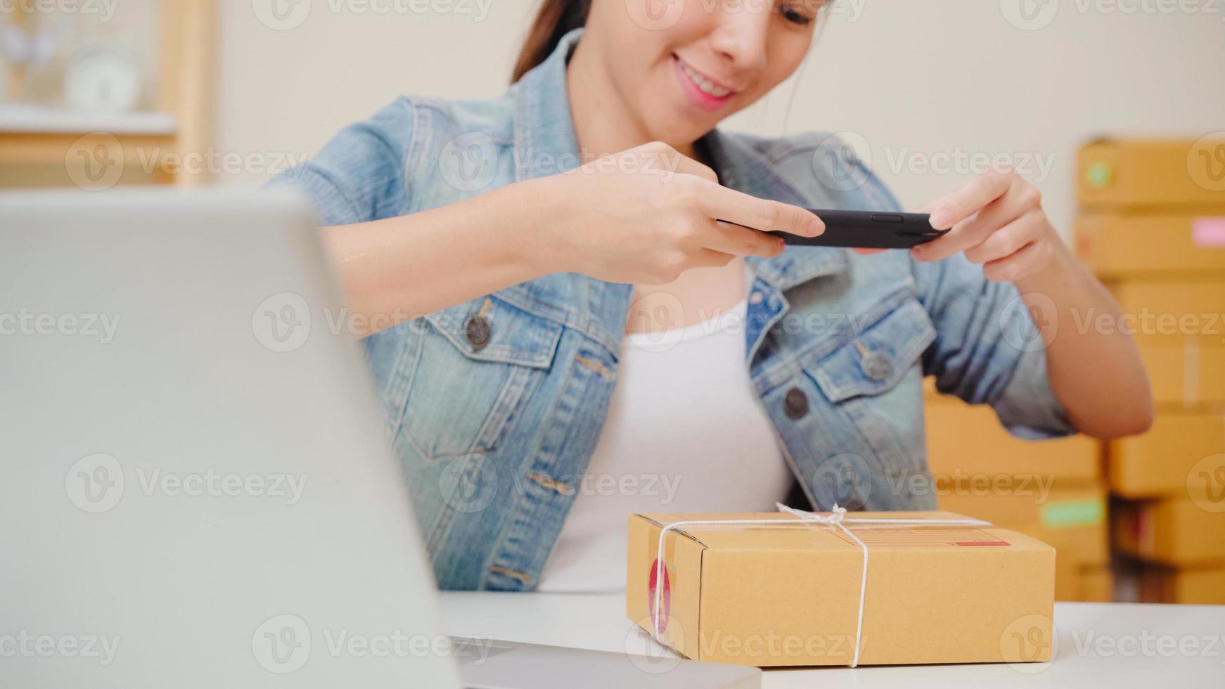 Beautiful smart Asian young entrepreneur business woman owner of SME checking product on stock scan qr code working at home. Small business owner at home office concept. photo