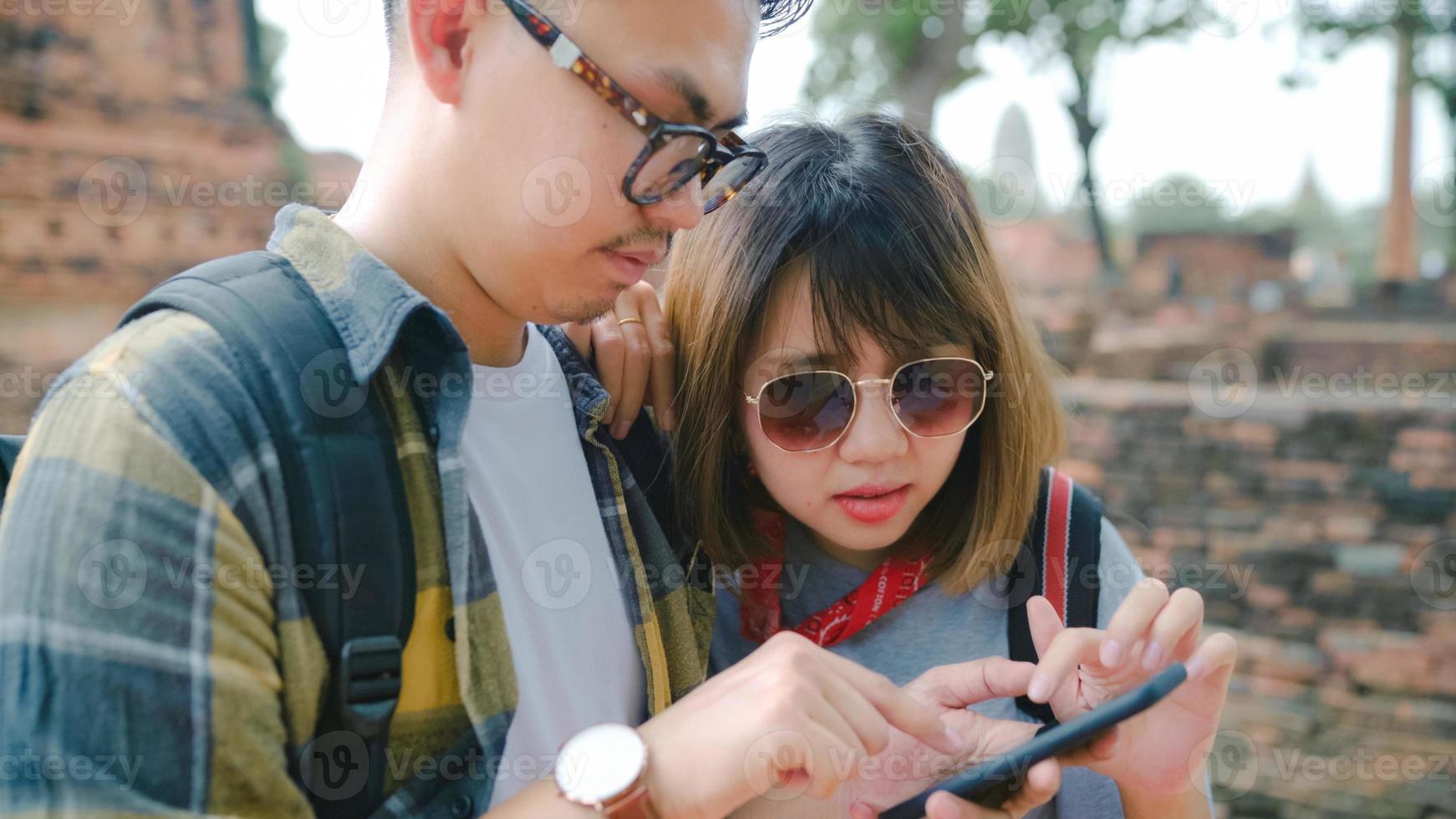 viajero pareja asiática que usa un teléfono inteligente para la dirección y mira el mapa de ubicación mientras pasa un viaje de vacaciones en ayutthaya, tailandia, la dulce pareja de mochileros disfruta del viaje en la ciudad tradicional. foto