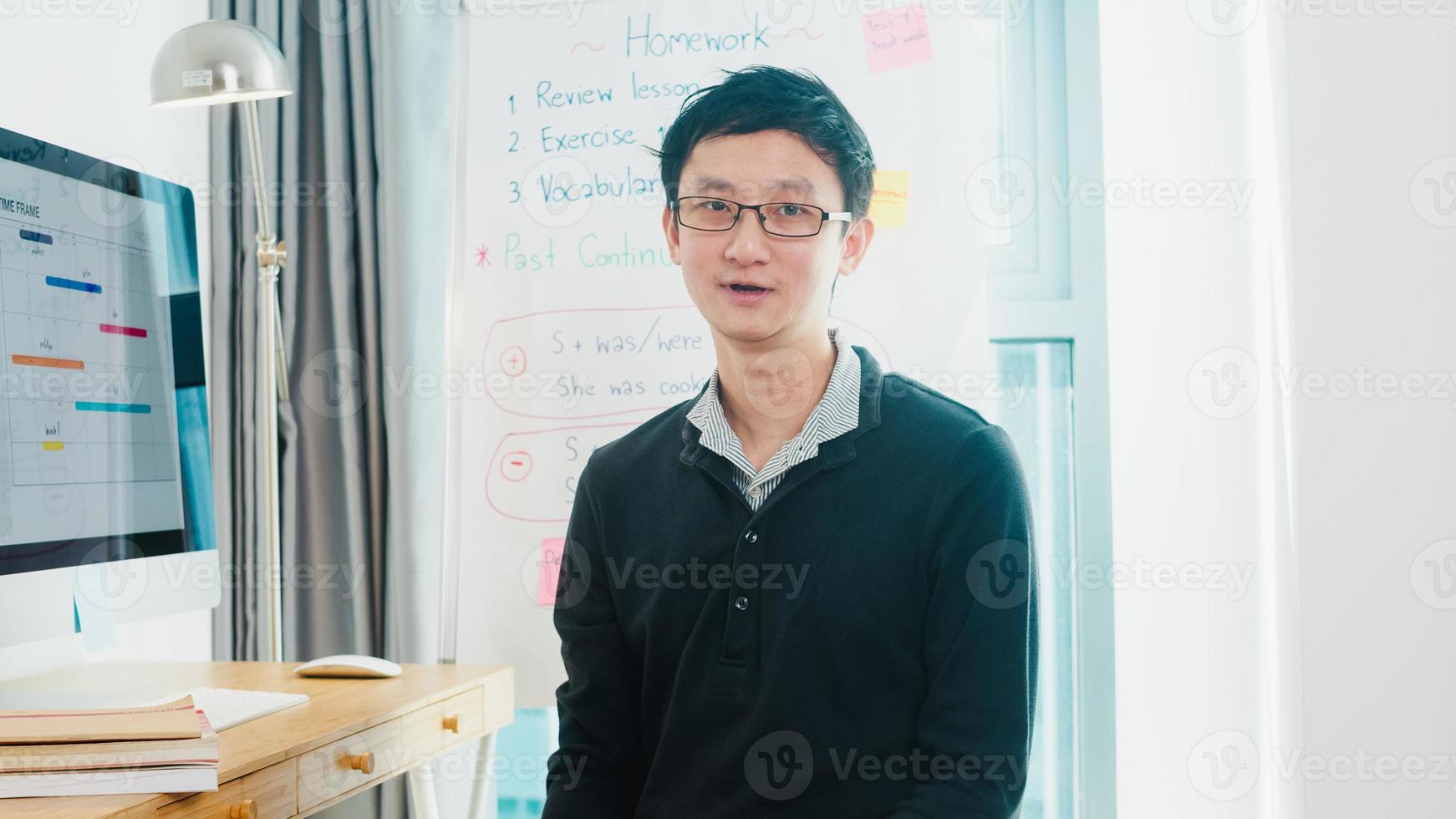 videoconferencia de un profesor de negocios masculino de mediana edad de asia mirando a la cámara hablar por cámara web aprender a enseñar en el chat en línea en casa. educación remota, distanciamiento social, cuarentena para la prevención del virus de la corona foto