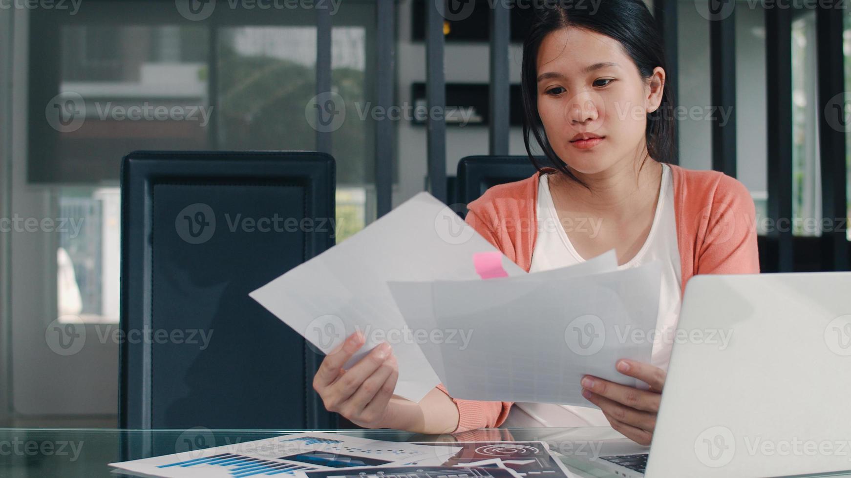 Young Asian Pregnant woman records of income and expenses at home. Mom girl happy using laptop record budget, tax, financial document, e commerce working in living room at home concept. photo