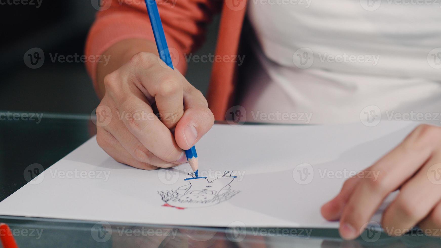 joven asiática embarazada dibujando bebé en vientre y familia en cuaderno. mamá se siente feliz sonriendo positiva y pacífica mientras cuida al niño en la mesa en la sala de estar en el concepto de hogar. foto