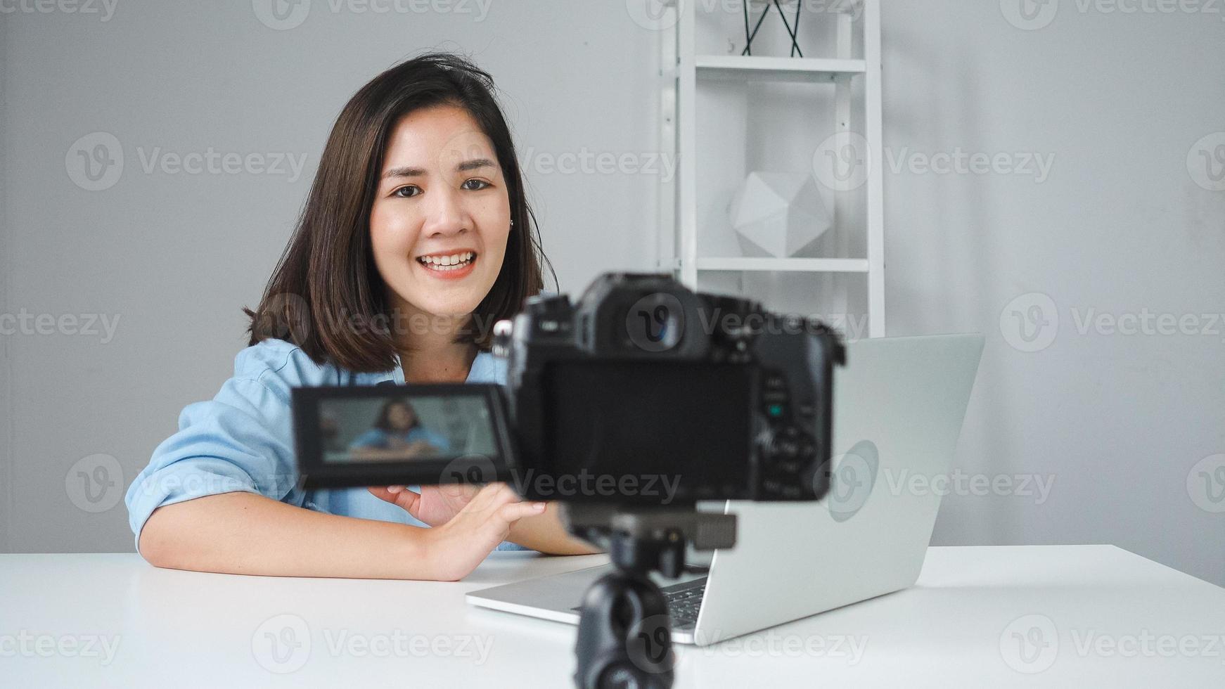 feliz hermosa mujer asiática responde a la pregunta de sus suscriptores. bloguera grabando video con una laptop desde la cámara para filmar un video de preguntas y respuestas. foto