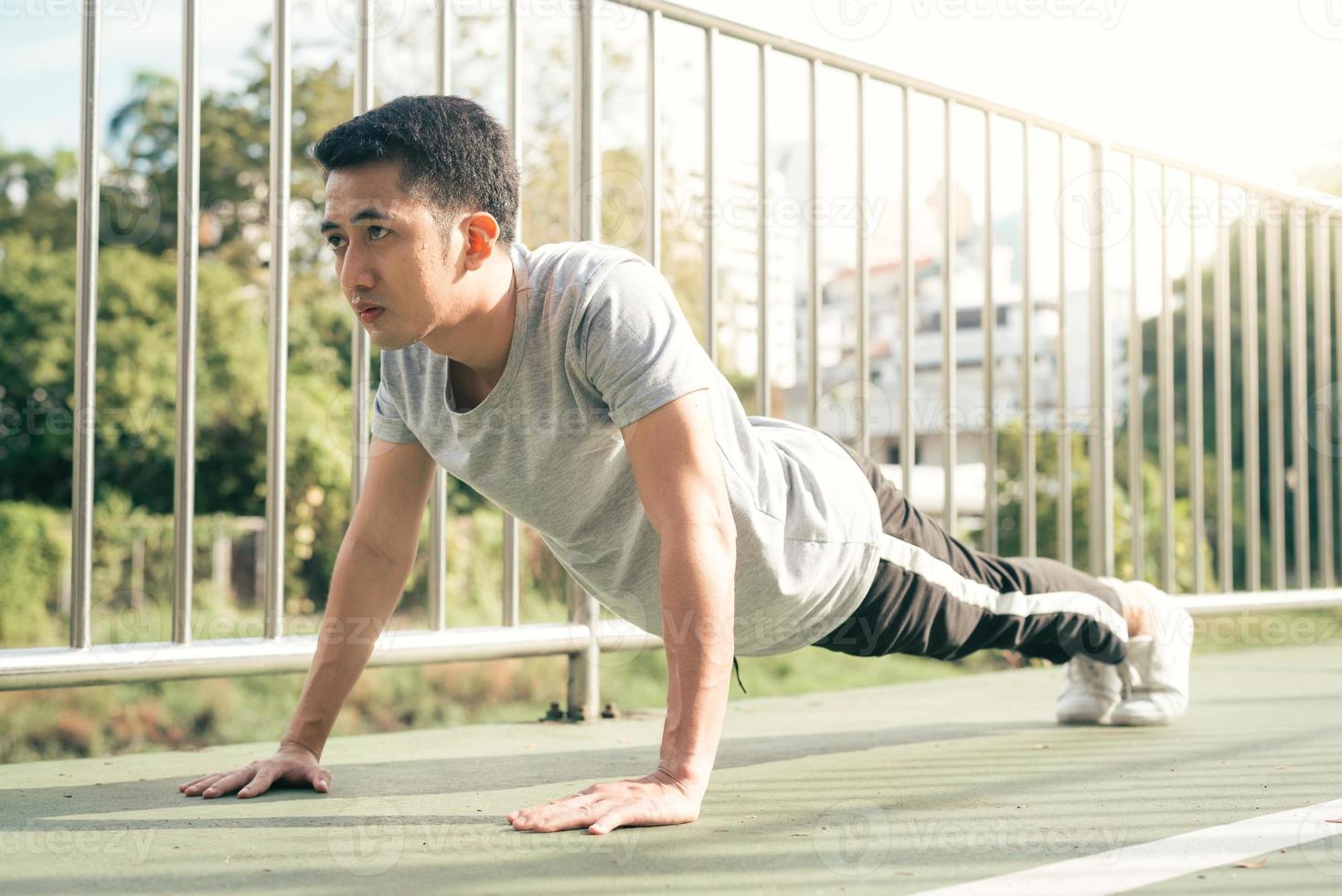 fitness deporte hombres moda ropa deportiva haciendo yoga fitness ejercicio en la calle. Un joven asiático en forma haciendo ejercicio de entrenamiento por la mañana. joven asiático feliz que se extiende en el parque después de hacer ejercicio. foto